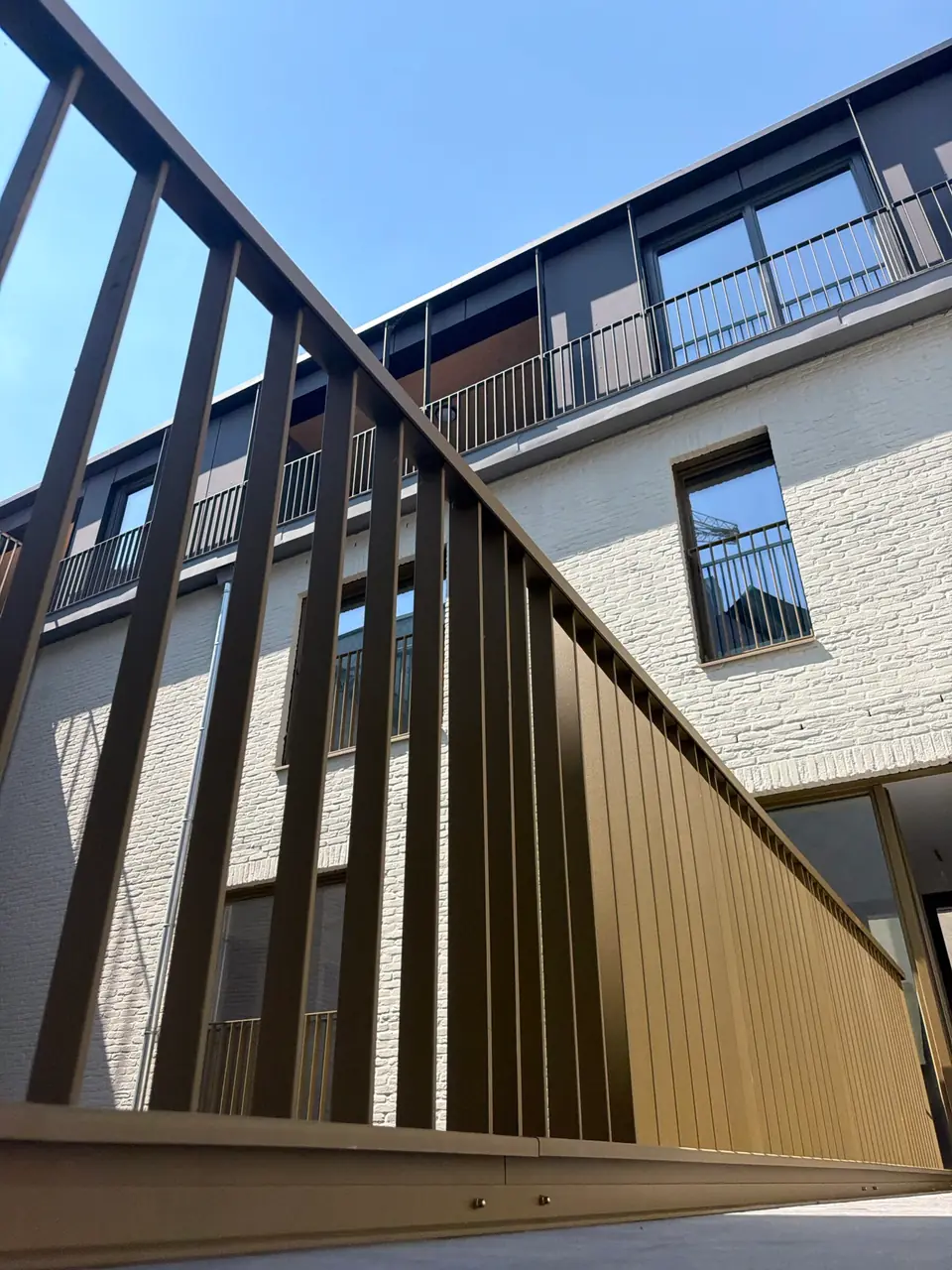 Garde-corps de balcons en acier patiné sur une façade claire